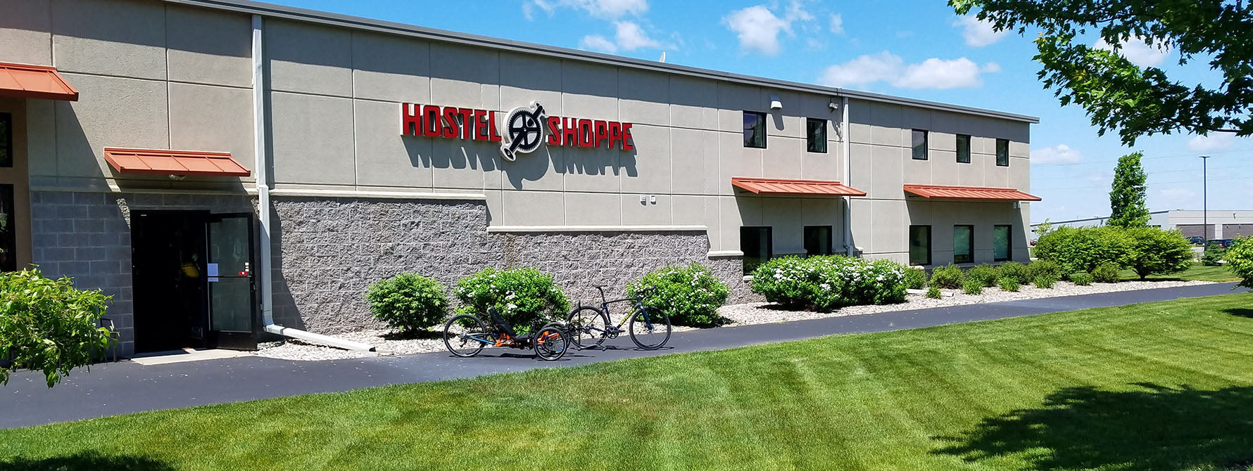 A summer photo of the Hostel Shoppe building with a recumbent trike and a bike in the foreground on the bike path.