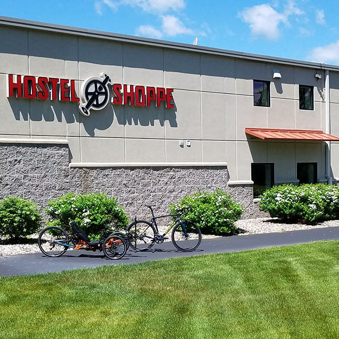 A summer photo of the Hostel Shoppe building with a recumbent trike and a bike in the foreground on the bike path.