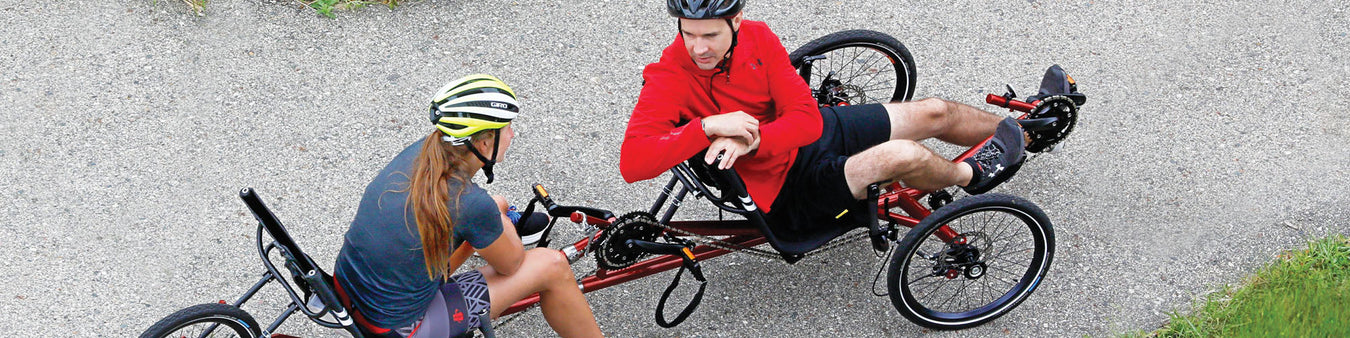 Two riders on a tandem recumbent trike stop to have a chaton the bike trail.
