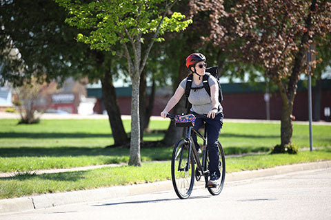 A woman commutes down a city street by bike with a backpack.