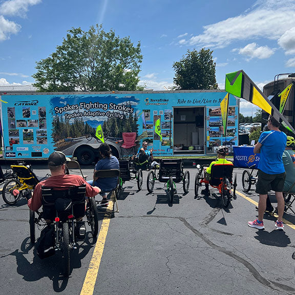A group of riders watch an adaptive cycling clinic.