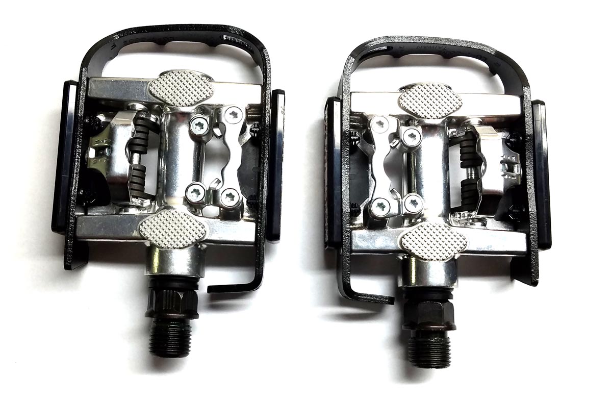 A pair of Wellgo clipless/platform take-off pedals for tricycles, featuring a black platform on one side and clipless design on the other, without cleats.