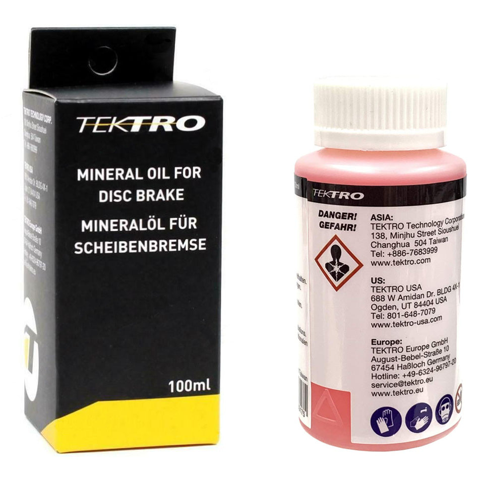 Bottle of Tektro Mineral Oil Brake Fluid 100ml next to black and yellow packaging box.
