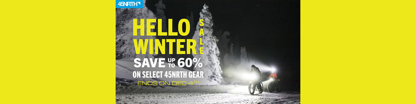 45NRTH "Hello Winter Sale - Save Up to 60% off select 45NRTH Gear - ends on Dec. 4th".  Two fat bikers ride through a nighttime snowy landscape.