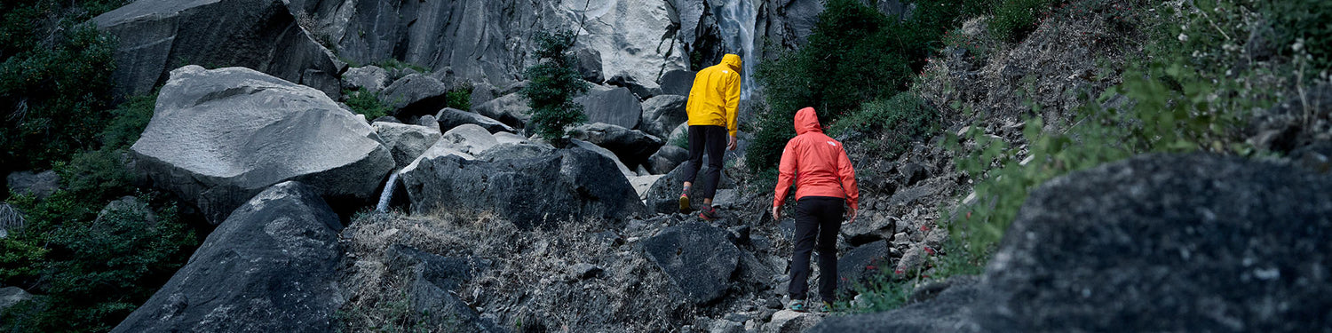 Two hikers climb some rocky terrain.