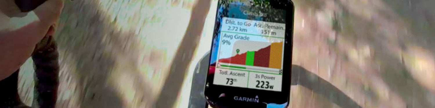 Image of a Garmin GPS bike computer attached to a bike stem, which the shadow of the road and a bike underneath.