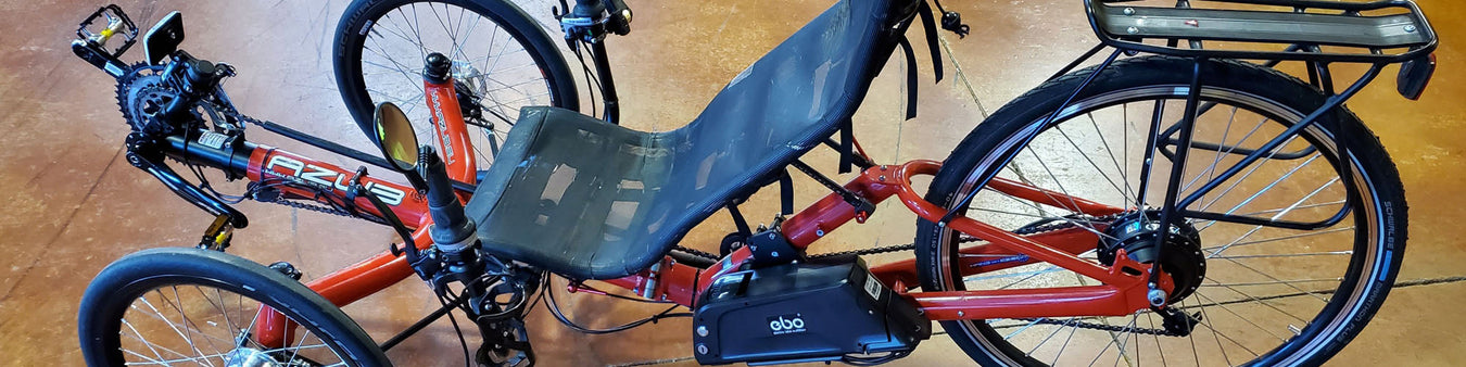 A red Azub T-Tris trike has been converted to electric assist with an Electric Bike Outfitters Hub Motor kit.
