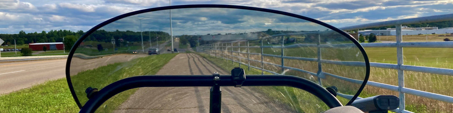 A view through a trike fairing going down the bike path.