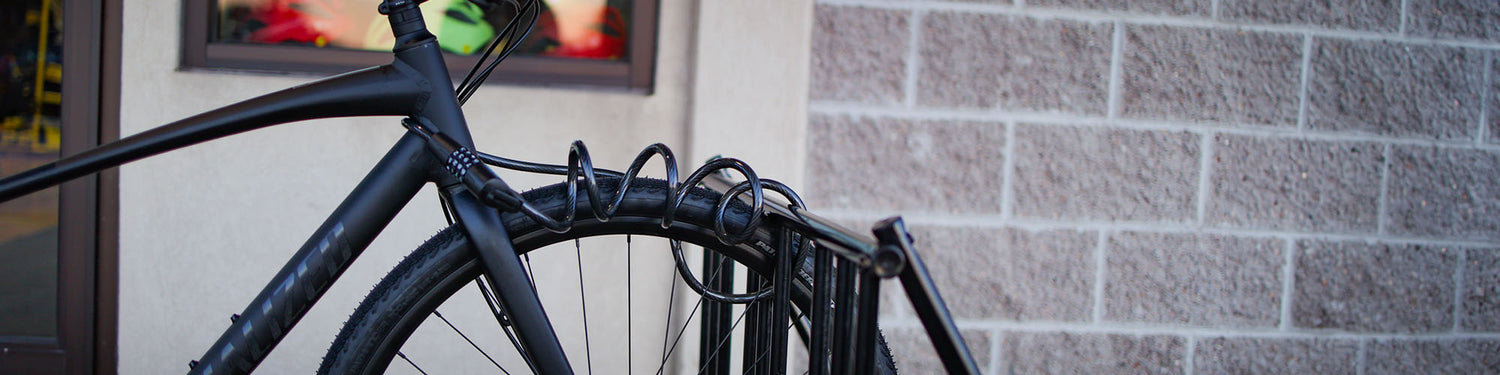 A bike is locked to a bike rack next to a gray brick building.