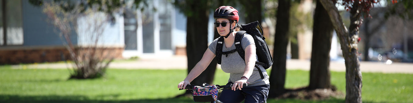A woman wears a pair of cycling sunglasses while she rides a bike on a sunny day.