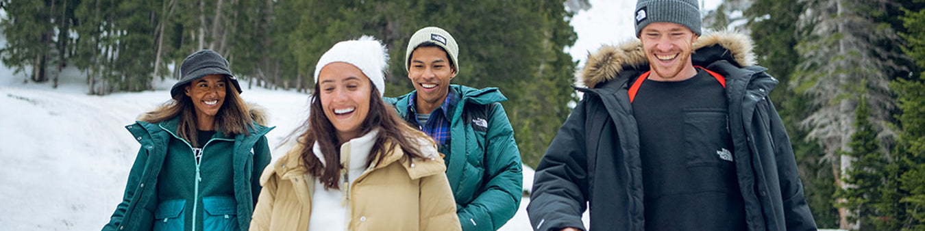 A group of men and women in winter apparel in a snowy landscape.