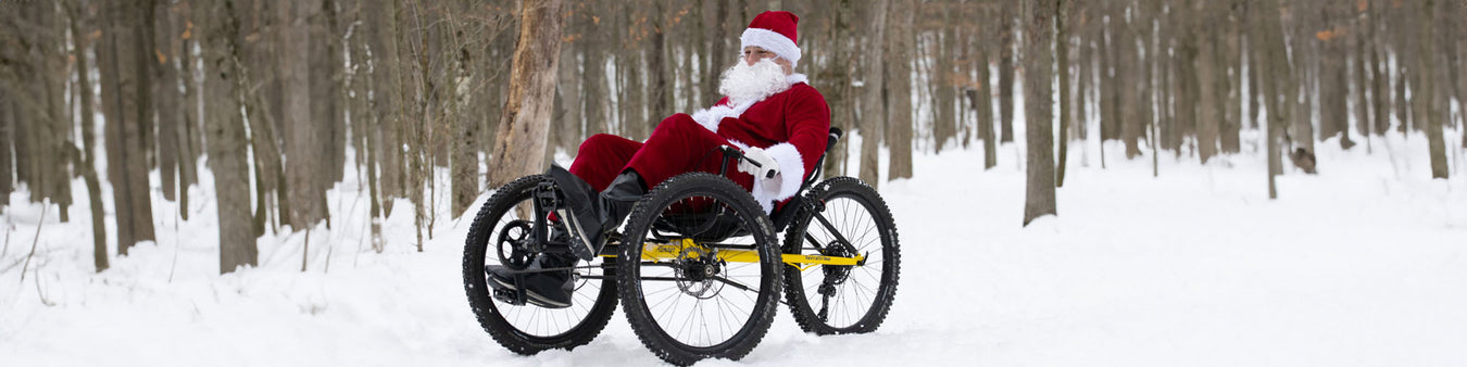 A man in a Santa suit rides a TerraTrike Rambler through the snowy woods.