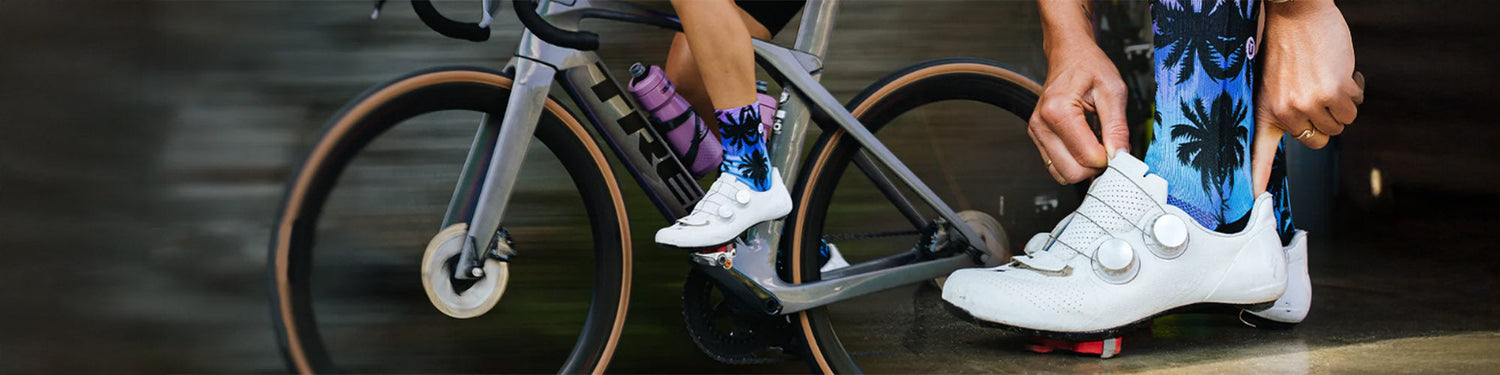 A closeup of a colorful Outway sock on a rider's leg both on and off a grey Trek bike.