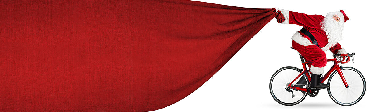 Santa is on a bicycle pulling a big red bag.