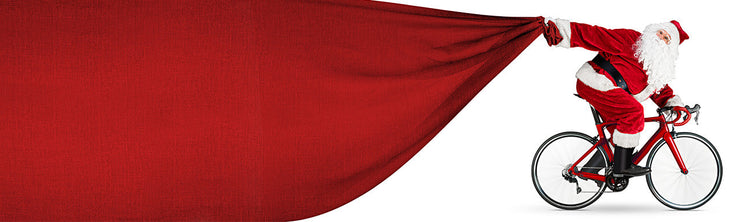 Santa is on a bicycle pulling a big red bag.