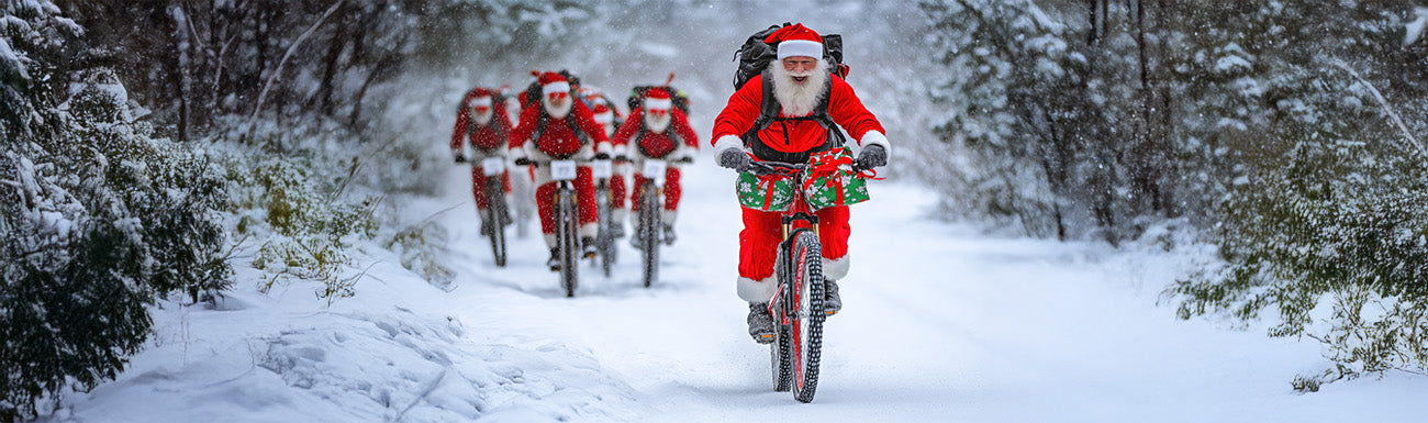 A group of Santa's ride through a snowy landscape on mountain bikes.