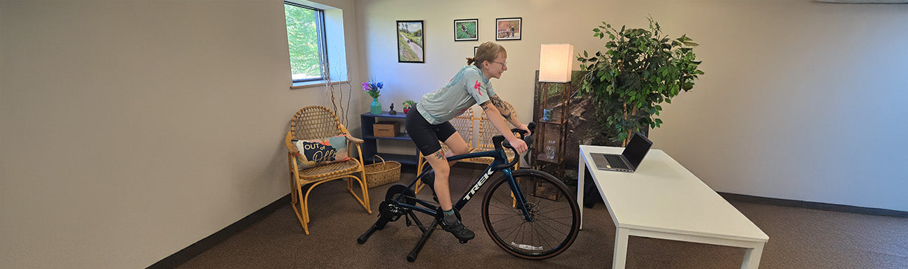 A women rides a Trek bike on an indoor stationary trainer.