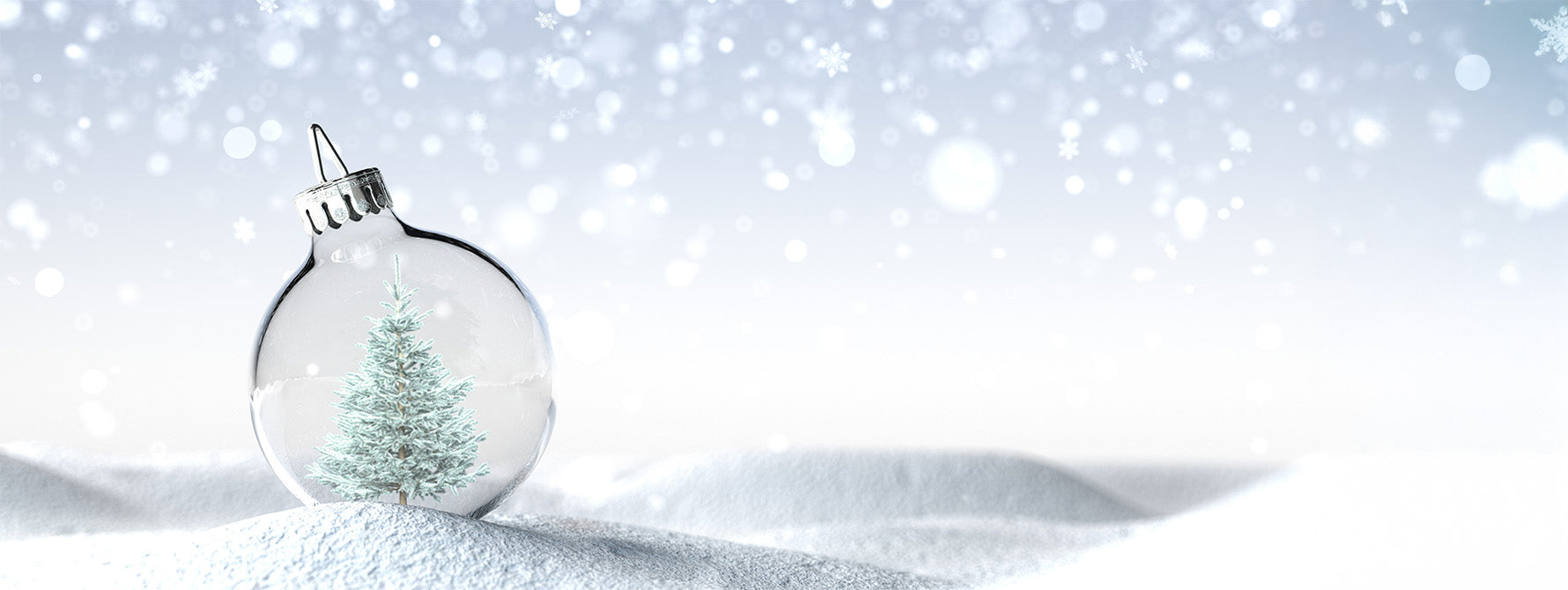 A snowy pine tree is instead a clear glass ornament against a snowy background.