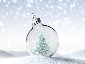 A snowy pine tree is instead a clear glass ornament against a snowy background.
