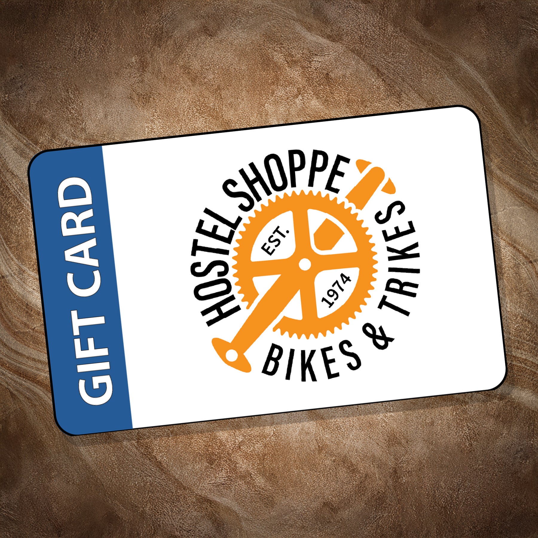 Hostel Shoppe Bikes & Trikes gift card on a wooden surface.
