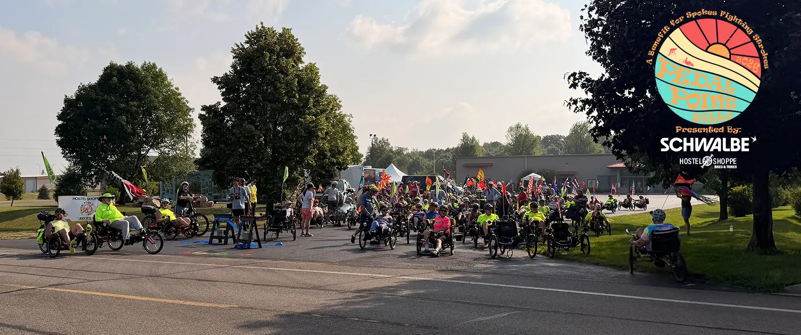 Riders gather for the Saturday morning rides at the Pedal Point Rally in front of the Hostel Shoppe on a sunny summer day. 