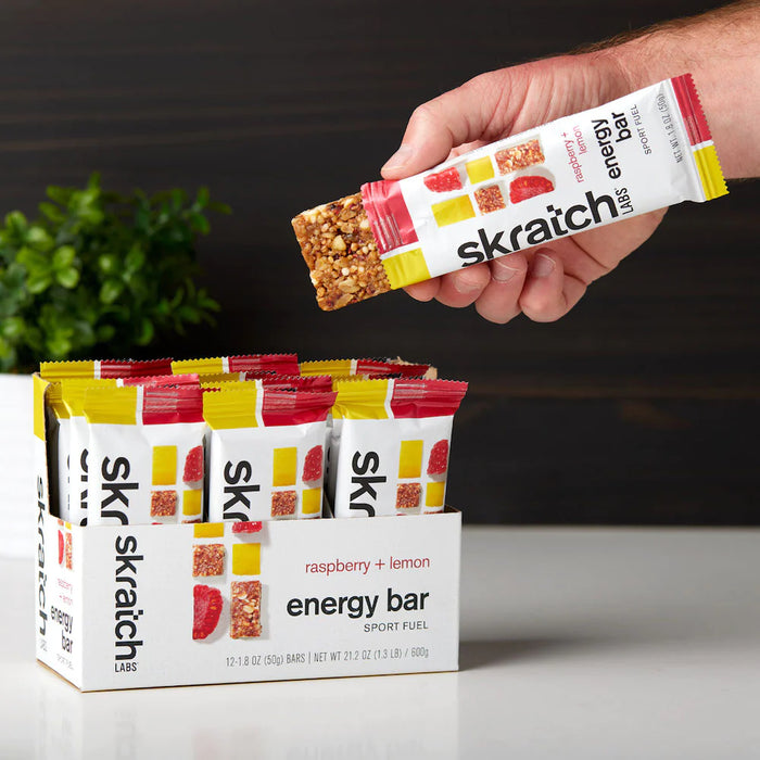 skratch-labs-anytime-energy-bar-box 12-lemon-raspberry-hand-holding-half-opened-bar