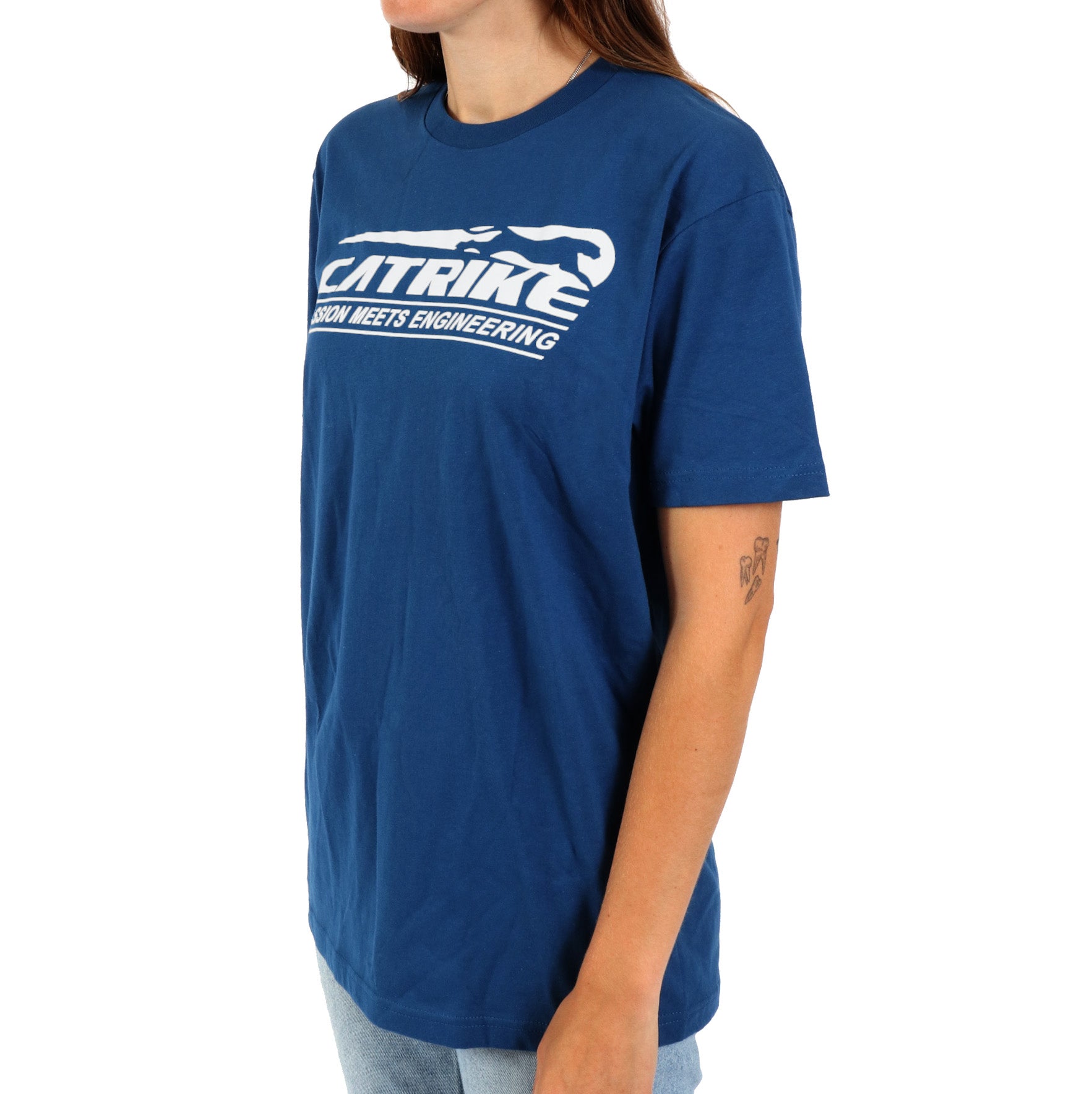 Studio front quarter view of woman wearing royal blue shirt with white Catrike logo across the chest and lettering that says Passion meets engineering below the logo.