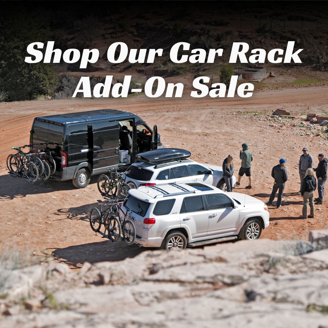 Vehicles with car racks and bicycles in a desert setting with text overlay that says "shop our car rack add-on sale."