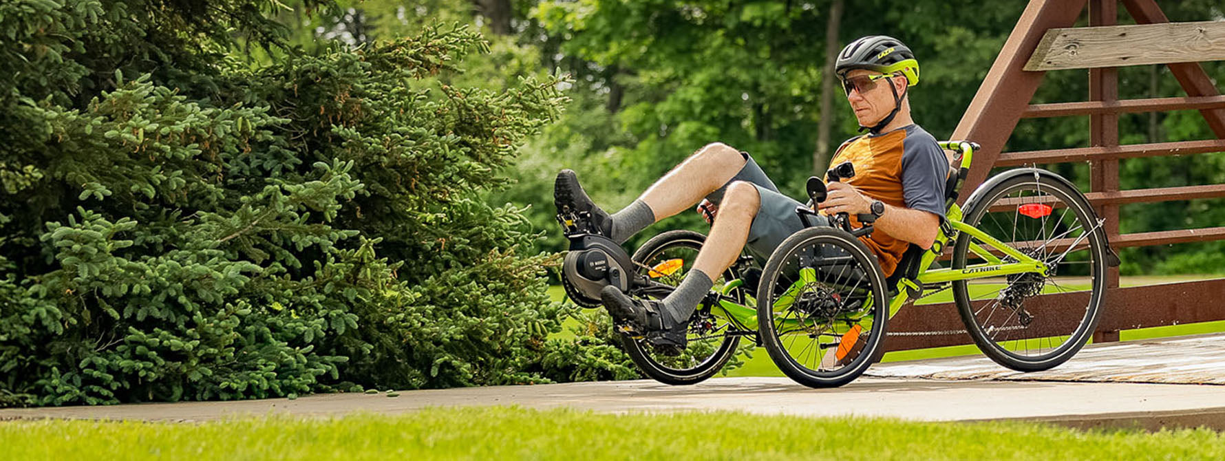 A man rides his electric assist trike down a bike path.