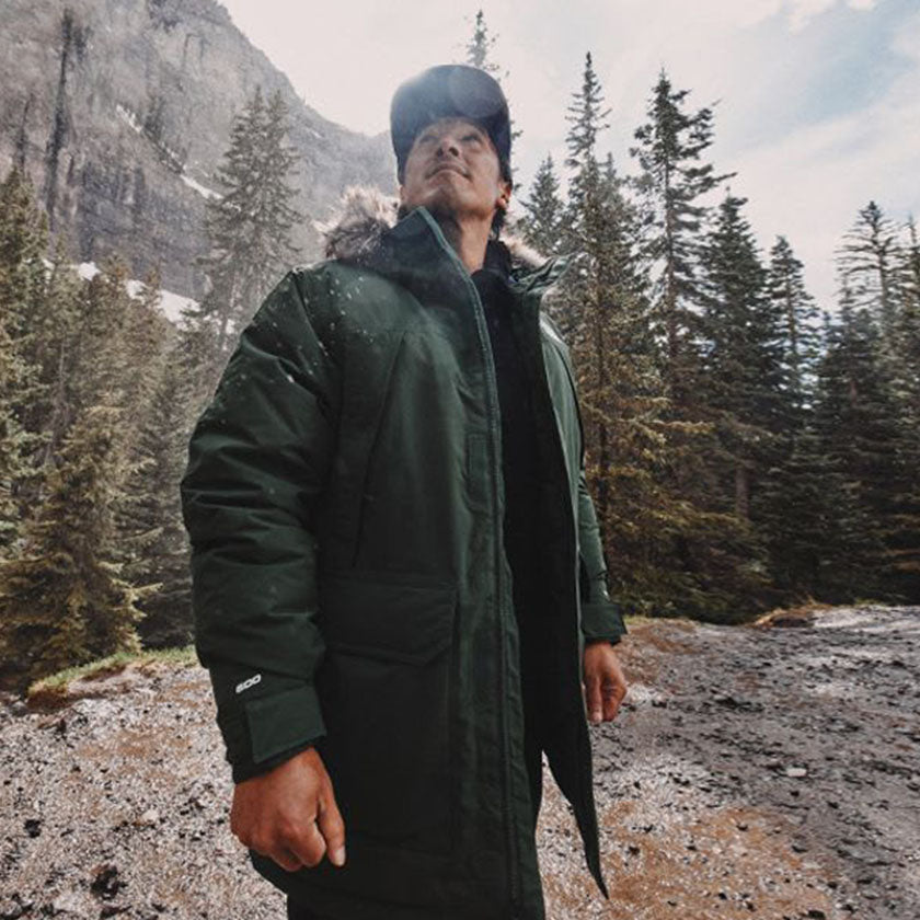 A man in wearing a jacket from The North Face looks up at the view in a wooded, mountianous area.