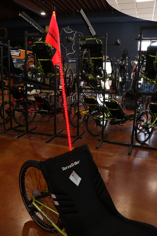 Red lighted four foot flag pole with orange triangle flag at top, installed on a green TerraTrike recumbent trike. 