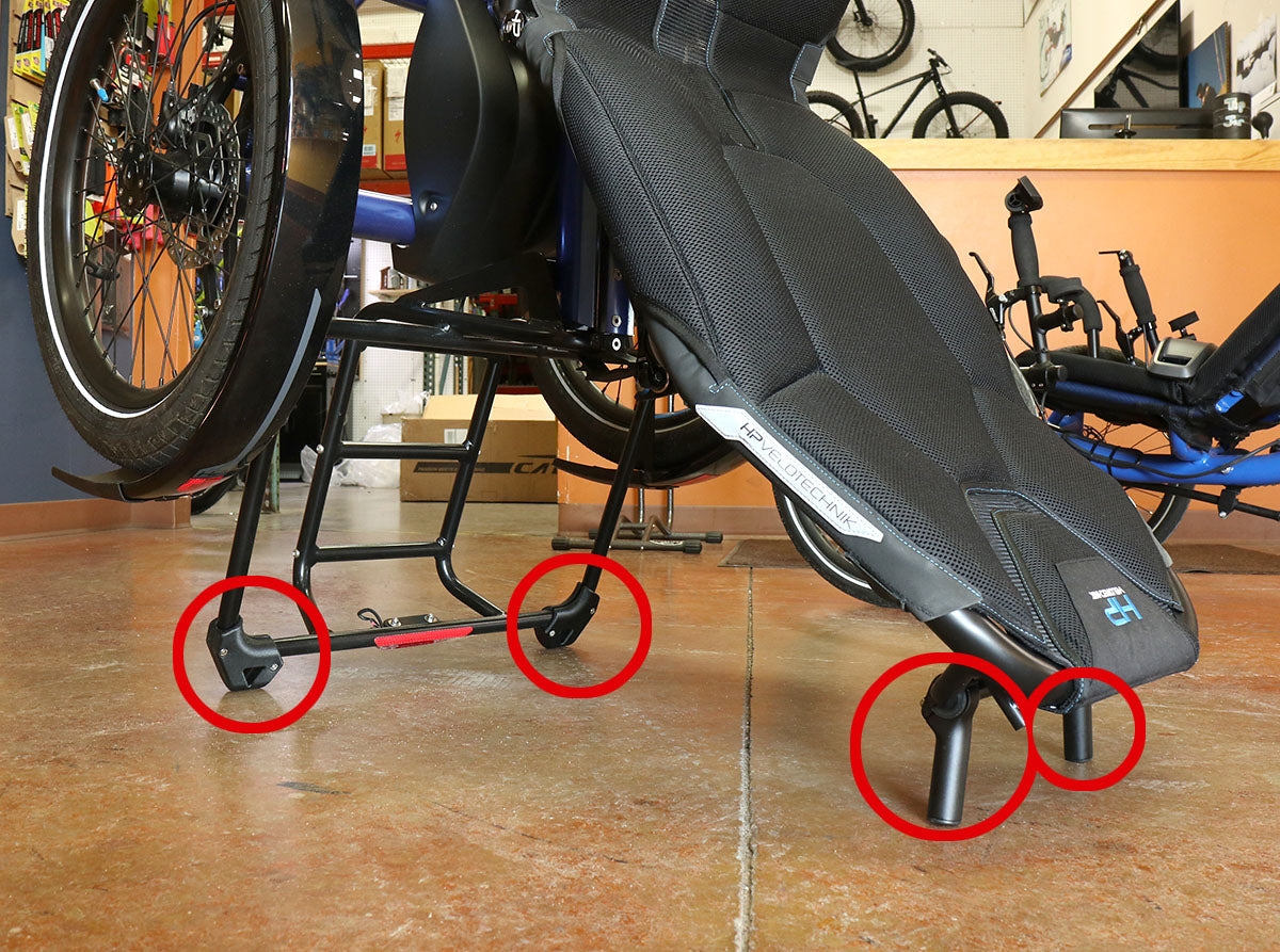 Close up side view of the HP Velotechnik stand-up feet kit installed onto the back of the seat and back of the rack of a HP Velotechnik Delta trike, with kit parts circled in red. 
