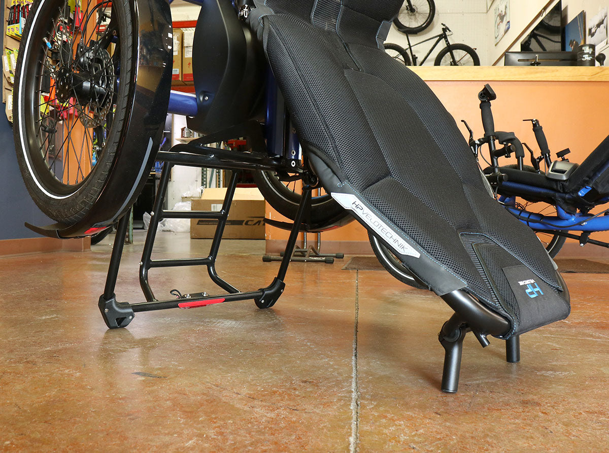 Close up side view of the HP Velotechnik stand-up feet kit installed onto the back of the seat and back of the rack of a HP Velotechnik Delta trike. 