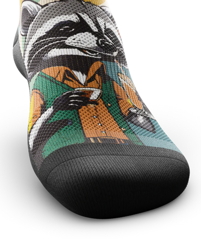 Top toe area of a multicolored  sock with racoon wearing brown button down shirt and green vest drinking cups of coffee. 