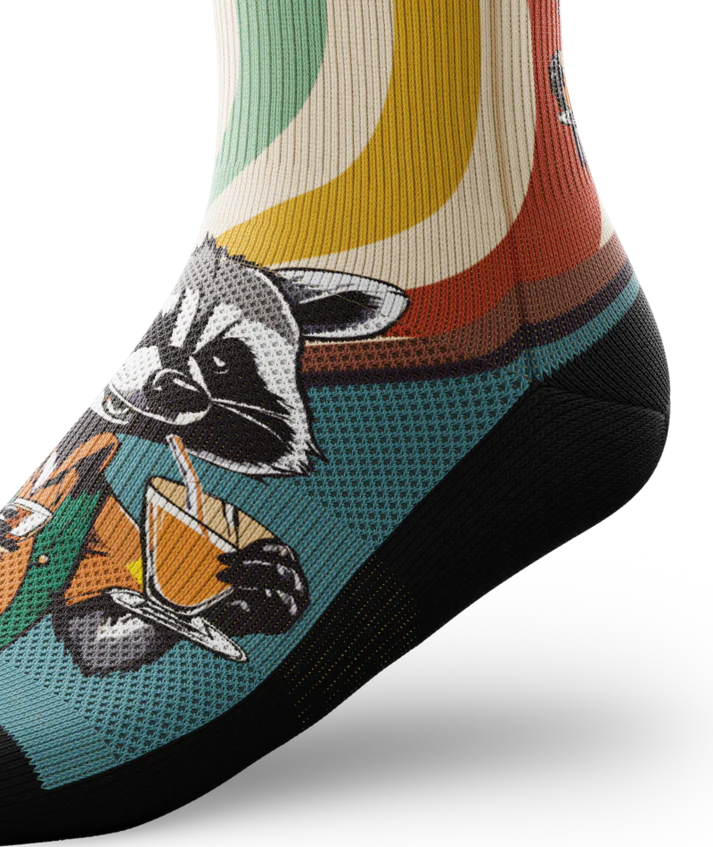 Side ankle view of a multicolored  sock with racoon wearing brown button down shirt and green vest drinking cups of coffee. 