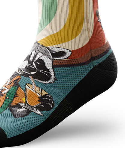 Side ankle view of a multicolored  sock with racoon wearing brown button down shirt and green vest drinking cups of coffee. 