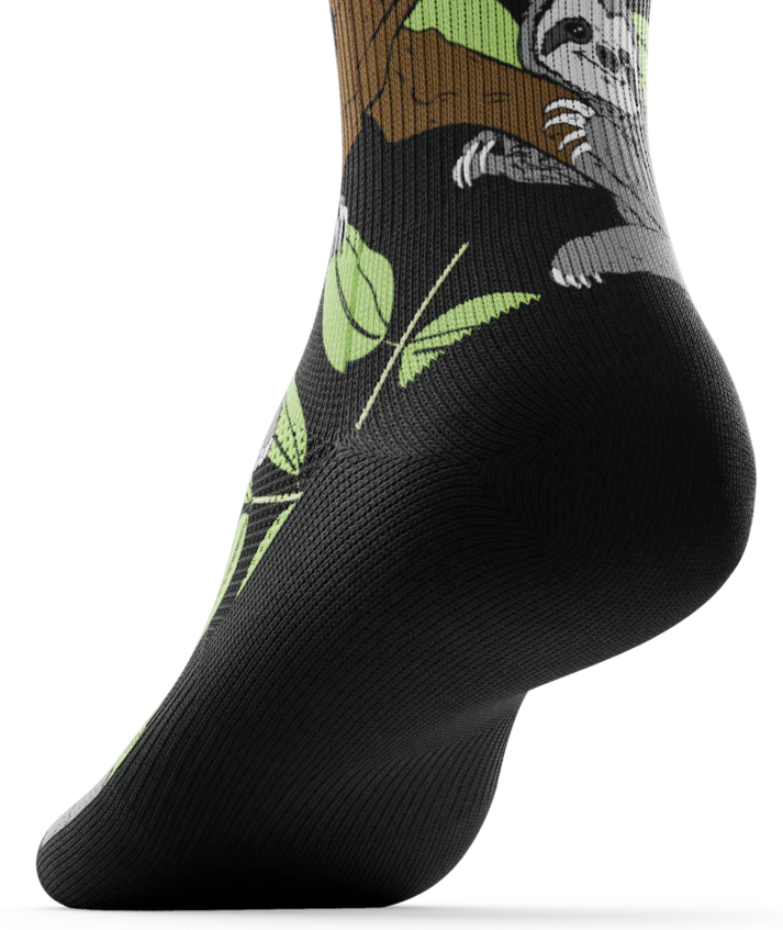 Bottom black sole view of sock with sloths in trees on main part of sock
