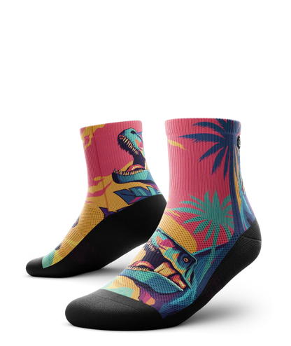 Multicolored  pair of socks with T-rex dinosaurs and palm trees on main part of sock, black soles. 