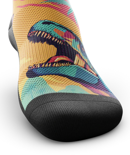 Top toe area of Multicolored sock with T-rex dinosaurs and palm trees on main part of sock, black soles. 