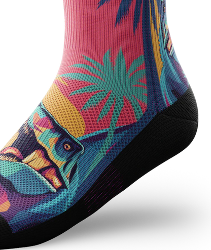 Side ankle view of Multicolored sock with T-rex dinosaurs and palm trees on main part of sock, black soles. 