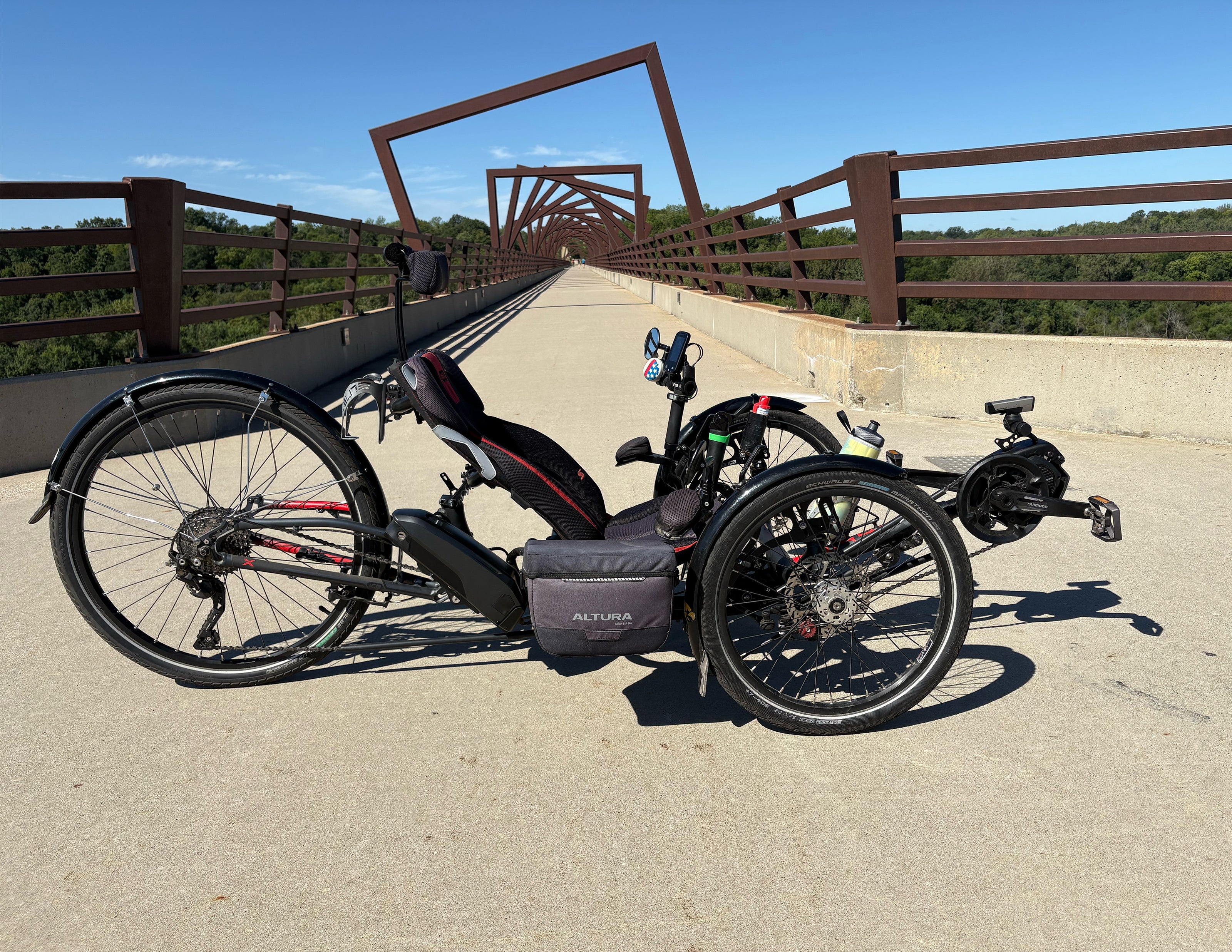 A recumbent trike on a bridge with a clear blue sky.