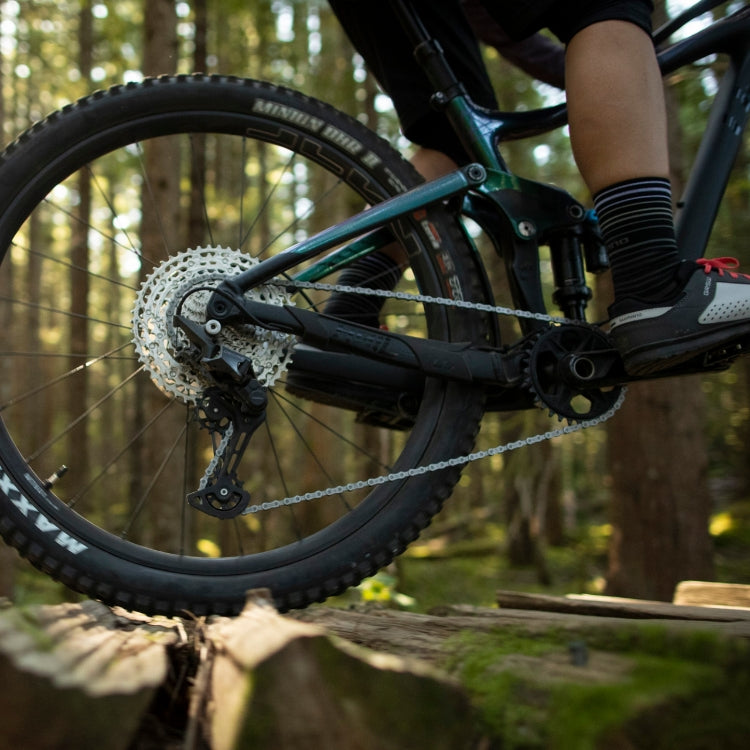 Shimano Deore CN-M6100 Hyperglide+ 126 Links Silver 12 Speed Chain on a mountain bike riding over logs