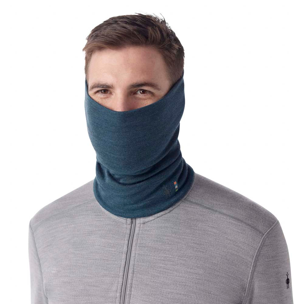 A man wearing the Smartwool Thermal Merino Reversible Pattern Neck Gaiter in Twilight Blue Heather pulled up over his face against a white background.