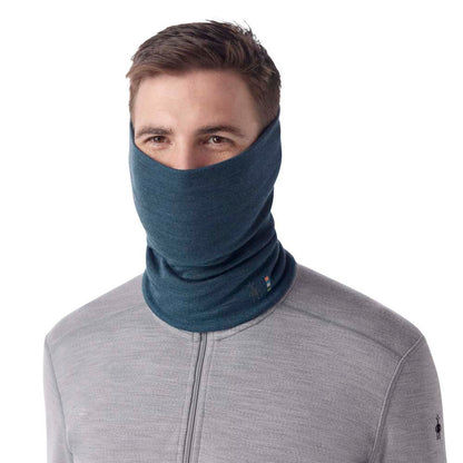 A man wearing the Smartwool Thermal Merino Reversible Pattern Neck Gaiter in Twilight Blue Heather pulled up over his face against a white background.