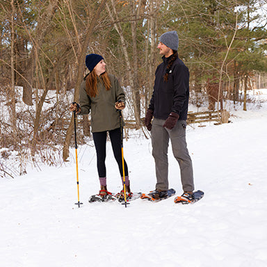 A man and a woman hike on showshoes.