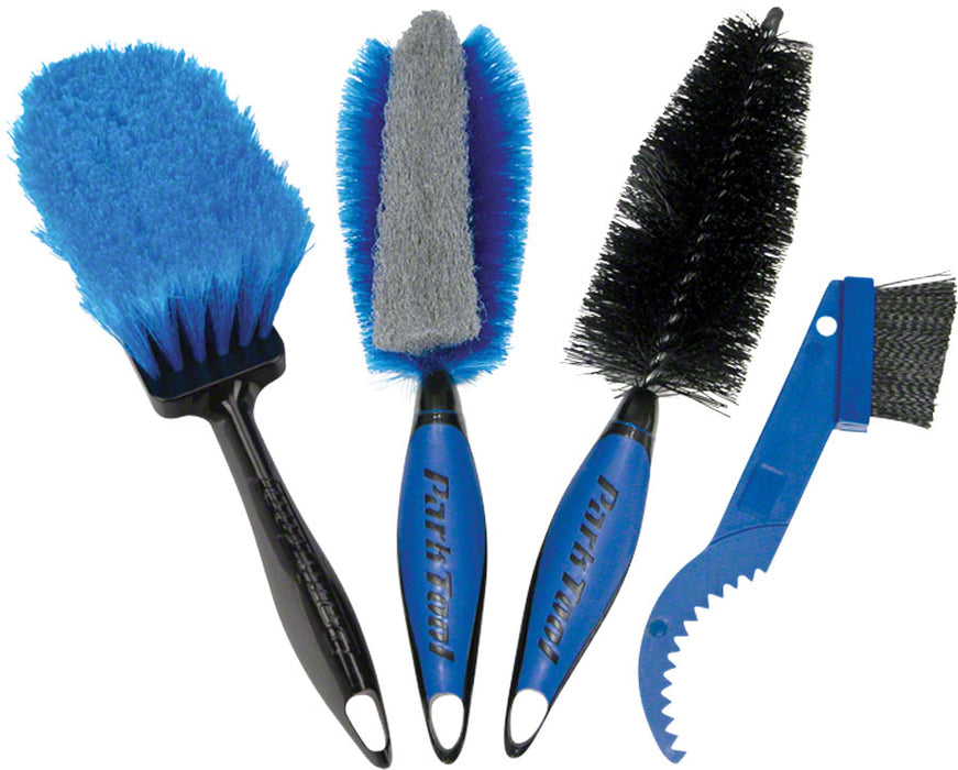 Set of four brushes, left brush has blue bristles and black handle, 2nd brush  has gray sponge along center and blue bristles on sides with black and blue handle, 3rd brush has black bristles and black and blue handle, and 4th tool has a blue handle with stiff black bristles and a curved toothed-plastic end.