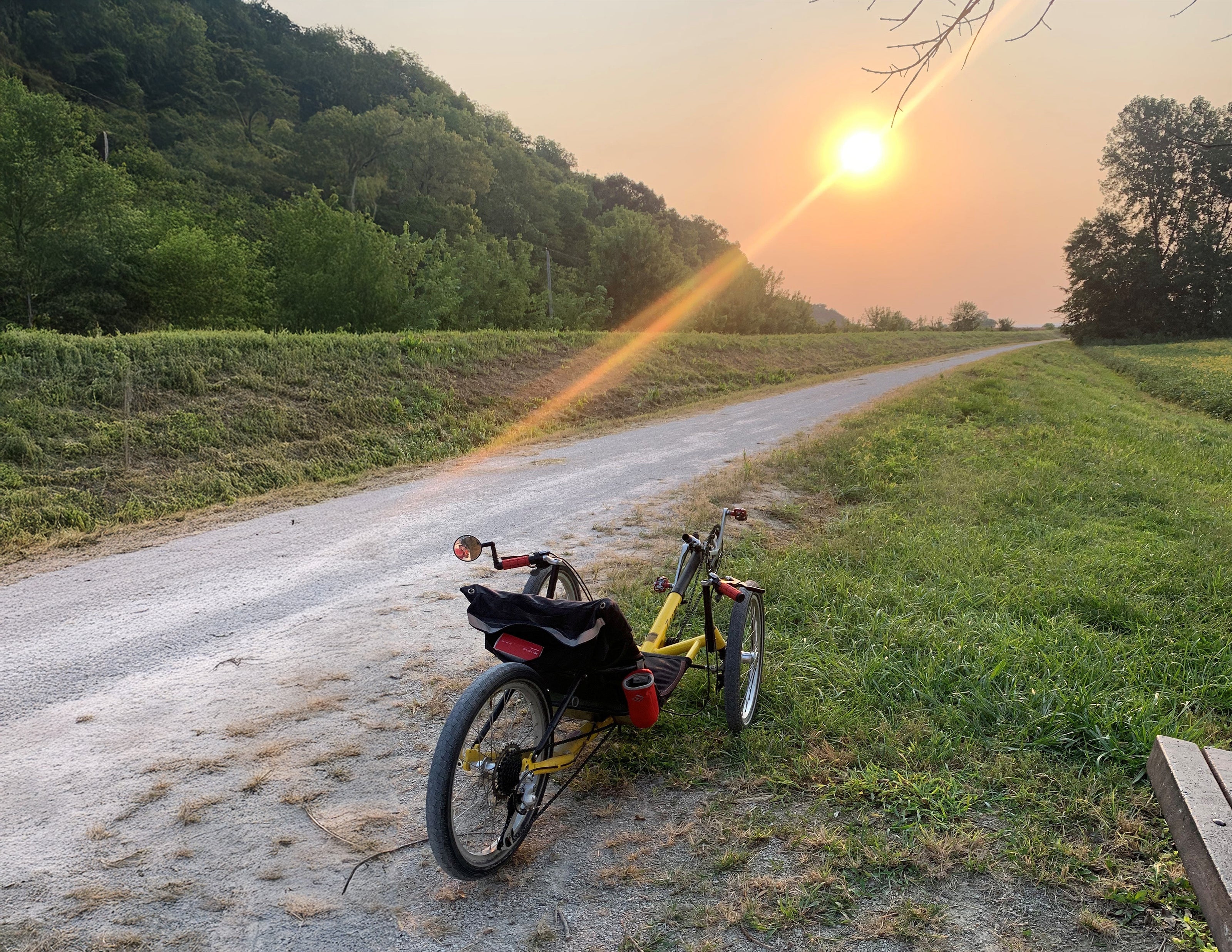 Recumbent trike on a rural road with a sunset in the background.