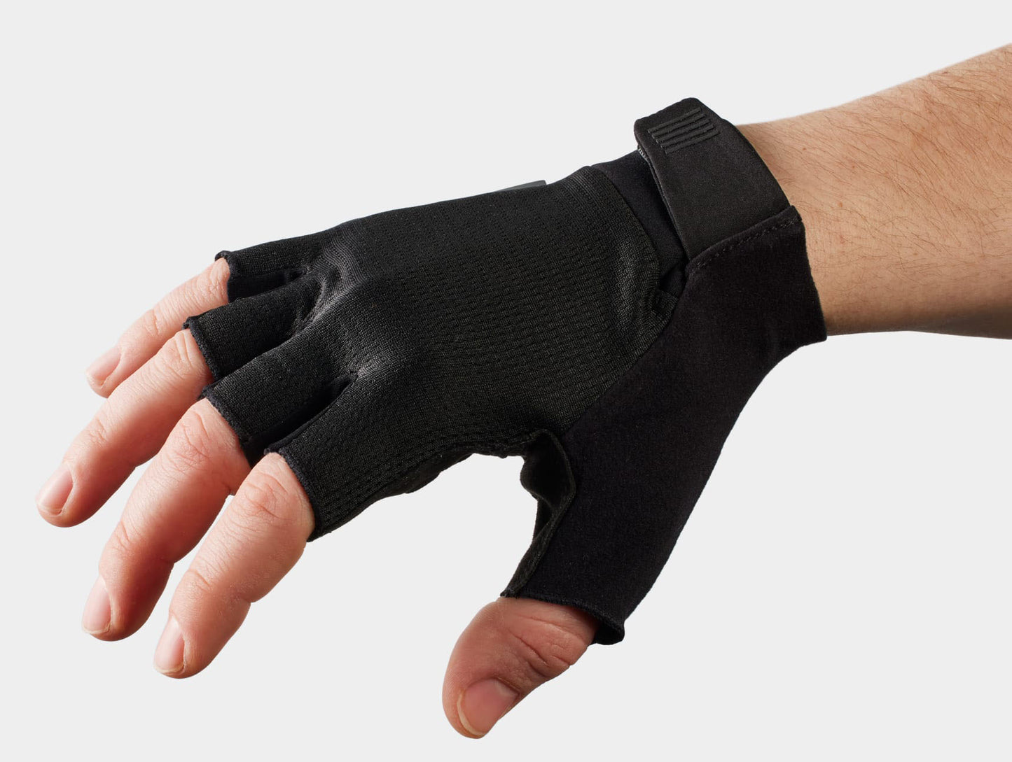 Studio back view of black short-finger cycling gloves with a black hook and loop strap across the back of the wrist.