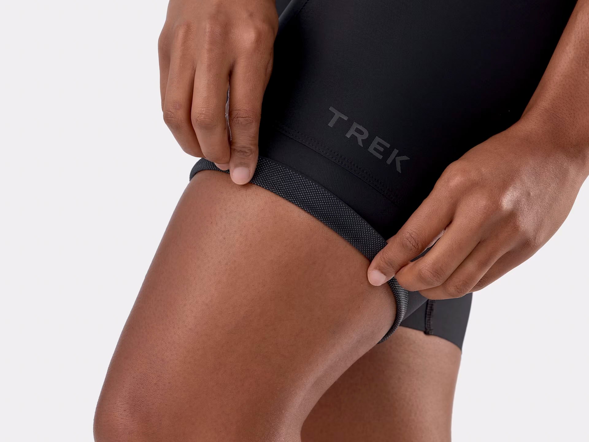 Studio bottom cuff view of black bib shorts highlighting the Trek logo above the hem and the grippy texture of the shorts to prevent them from creeping up while riding. 