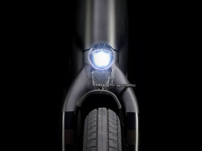 Front view of the Trek Verve+ 3 Lowstep Gen 3 e-Bike in Black, shown on a black background. It includes fenders, lights, rear rack, suspension seatpost, and kickstand.
